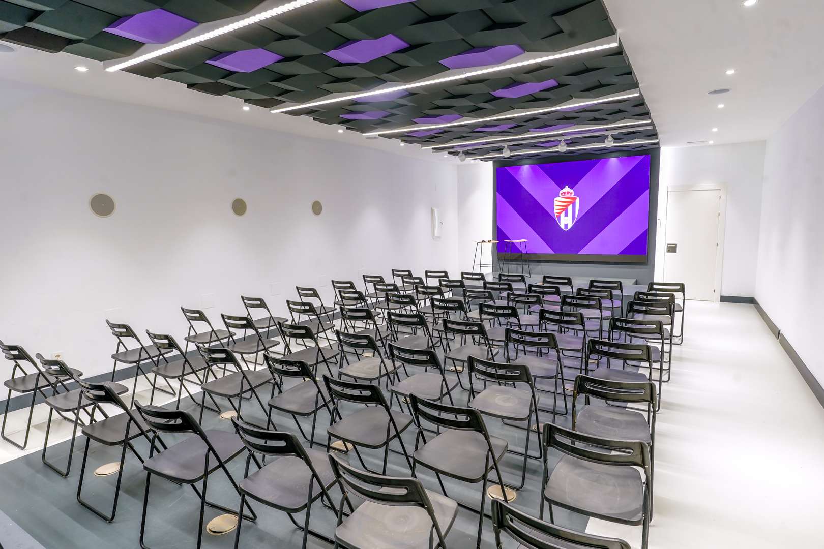 Sala con muchas sillas y una gran pantalla al fondo